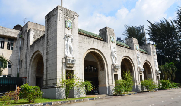 A light-grey building with arched entranceways and statues on the facade.